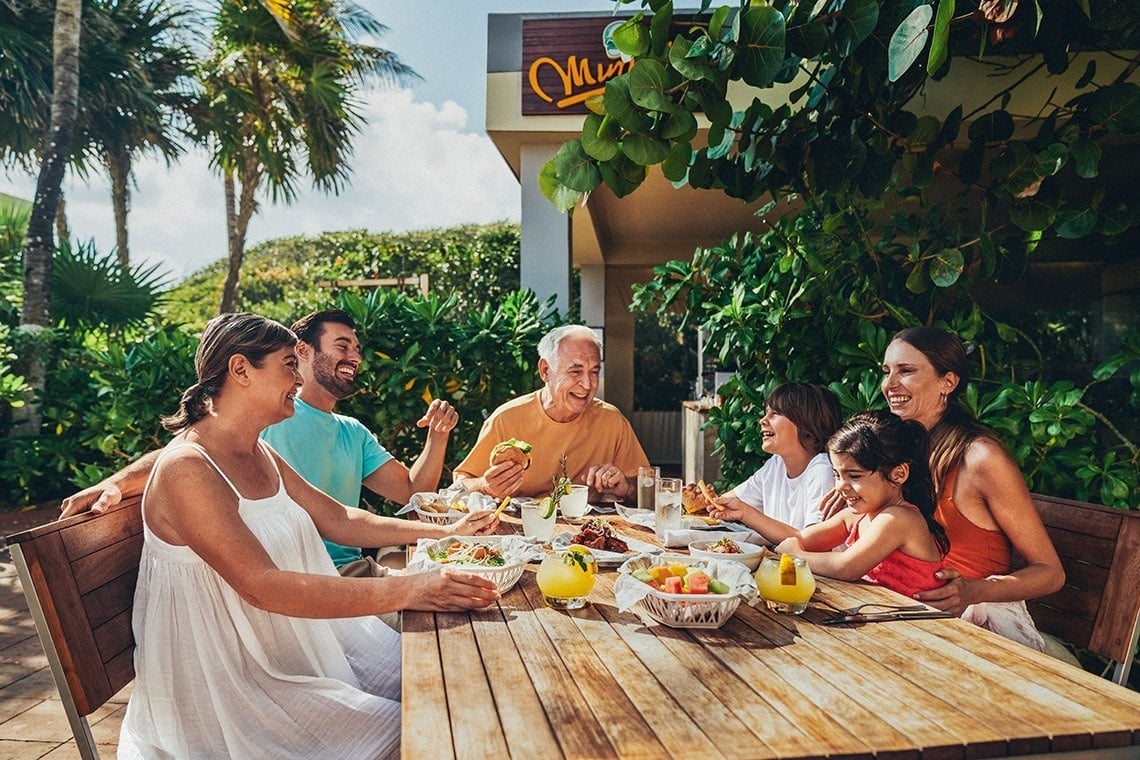 um grupo de pessoas está sentados em torno de uma mesa comendo comida