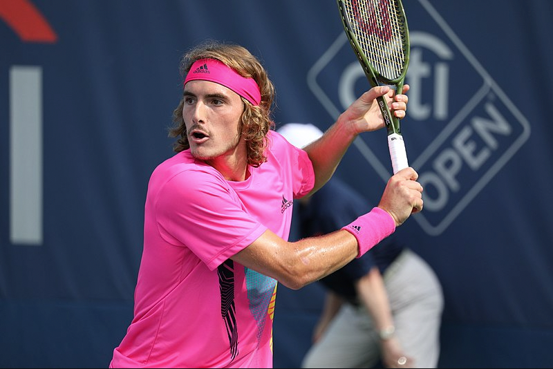 a man in a pink shirt is holding a tennis racquet in front of a citi open sign