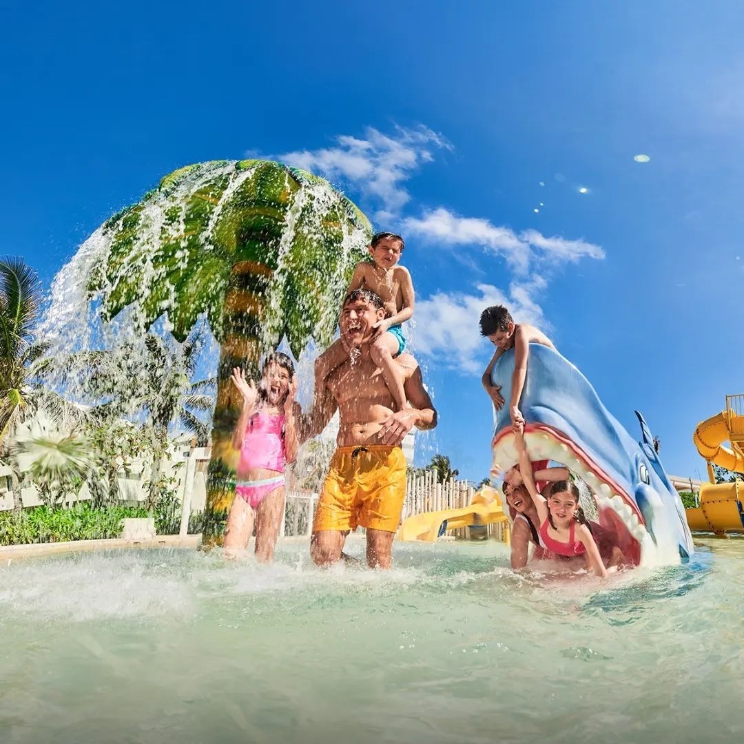 Padre con hijos jugando en parque acuático de Park Royal hoteles y resorts