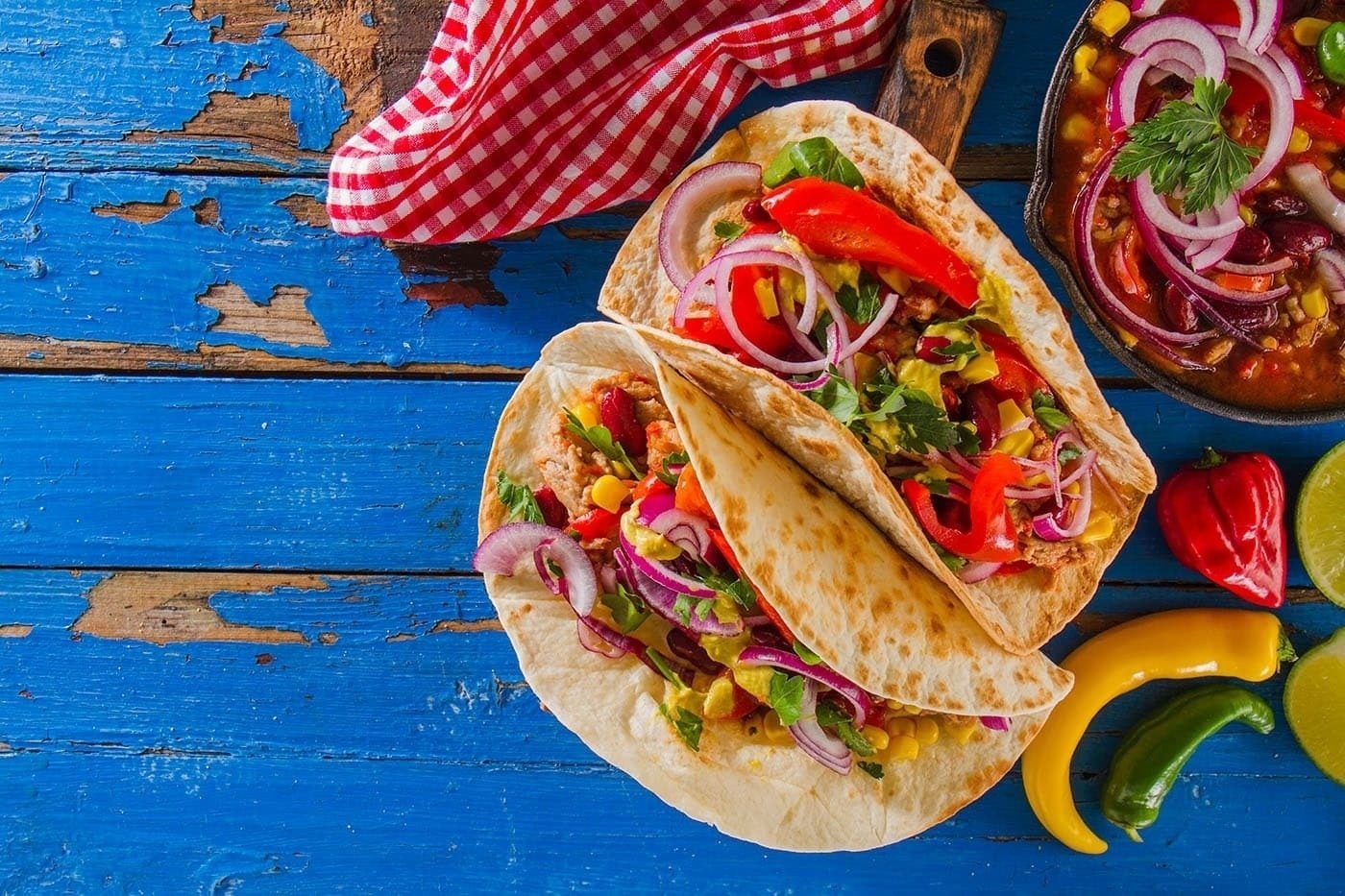 two tacos with vegetables on a blue wooden table