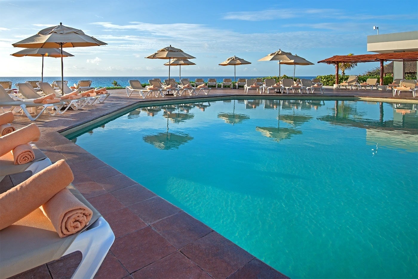 Hotel Park Royal Beach Cancún: piscina con vista al mar, camastros y sombrillas.