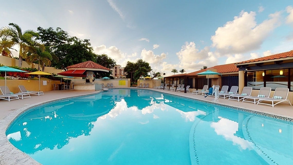 a large swimming pool surrounded by chairs and umbrellas