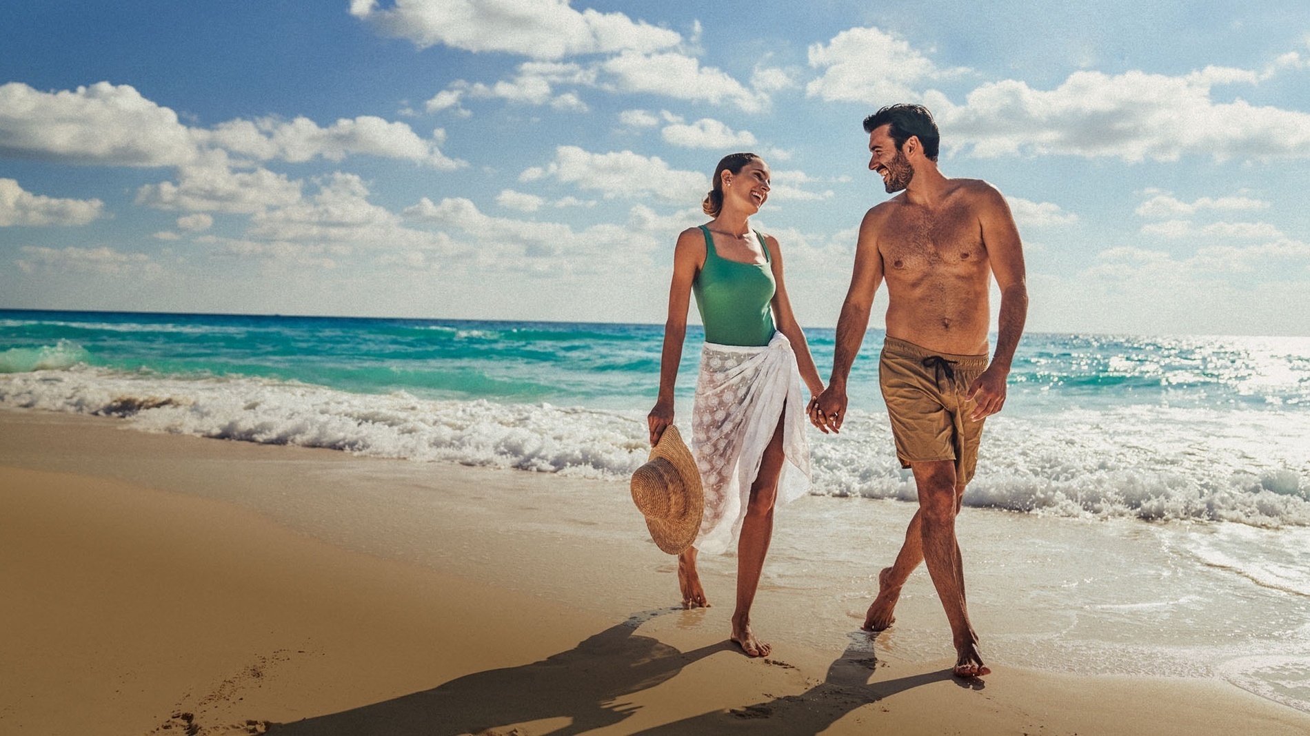 a man and a woman are holding hands on the beach