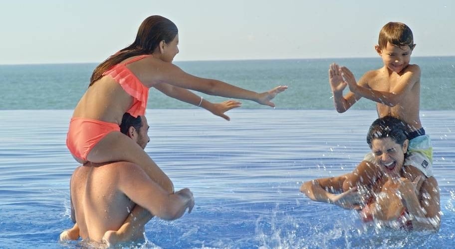 Familia jugando en la piscina infinity en el hotel Beach Mazatlán en México 
