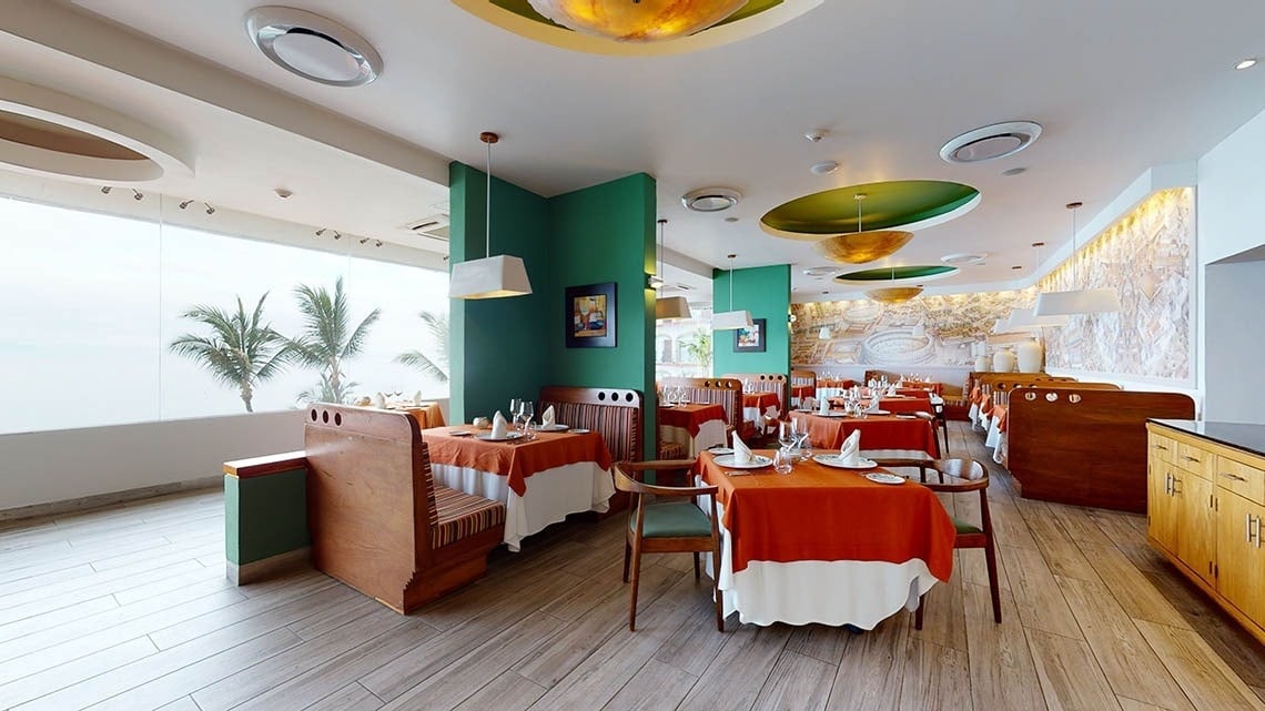 Mesas e cadeiras com cores quentes do restaurante italiano Andiamo do Hotel Grand Park Royal Puerto Vallarta