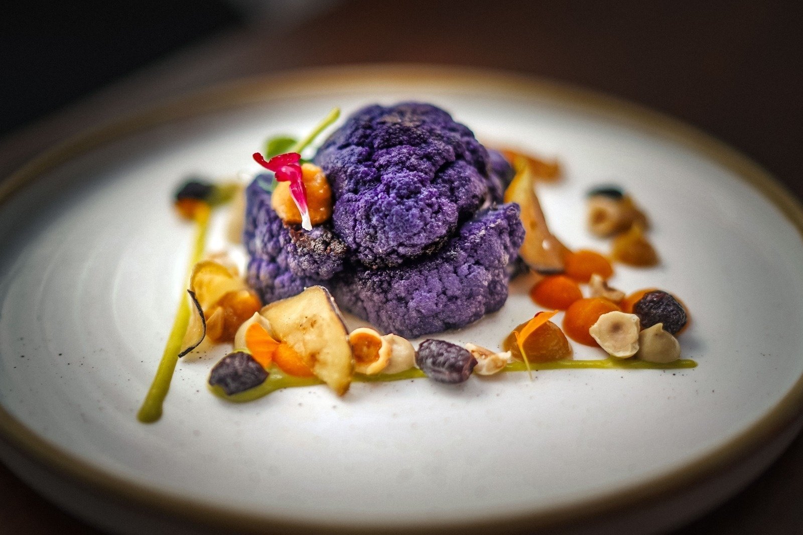 a white plate topped with purple cauliflower and nuts