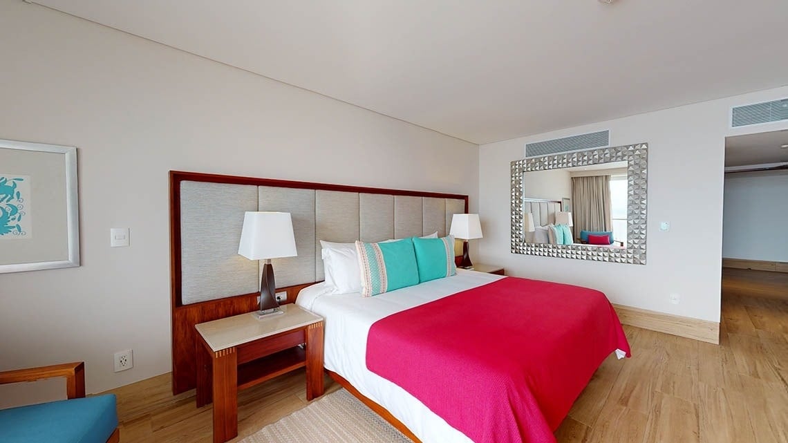Room with bed, armchair and mirror of the Hotel Grand Park Royal Puerto Vallarta