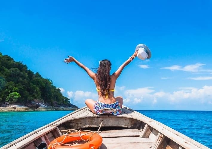 a woman in a bikini is sitting on the back of a boat in the ocean .