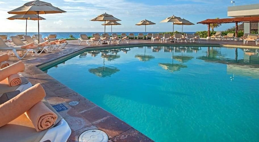 Piscina con sus hamacas y toallas enrolladas, con vistas a la playa de Cancún, caribe mexicano
