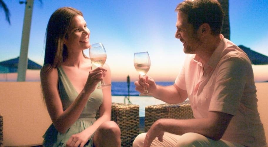Couple drinking a cocktail with the beach in the background