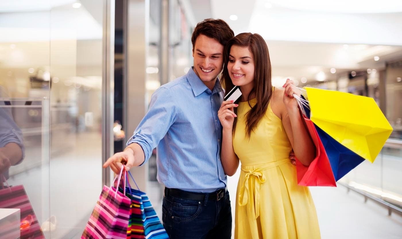 a man and woman are shopping in a mall and the woman is holding a credit card