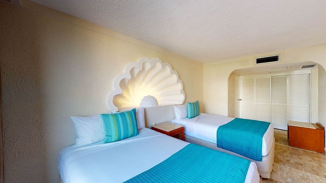 Habitación con dos camas y luz en la pared en forma de concha marina del Hotel Park Royal Beach Acapulco