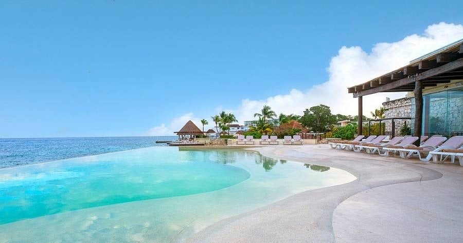 an infinity pool surrounded by chairs overlooking the ocean