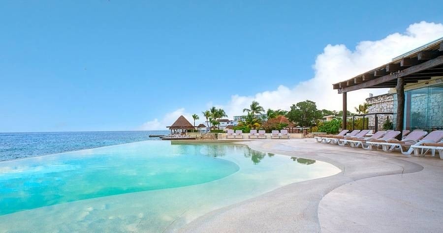 uma piscina infinita em um resort com vista para o oceano .