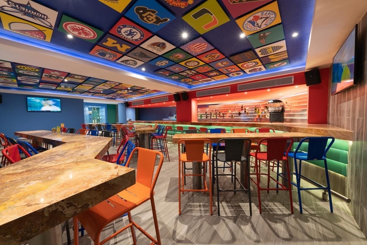 a sports bar with tables and chairs and a ceiling with logos for various teams