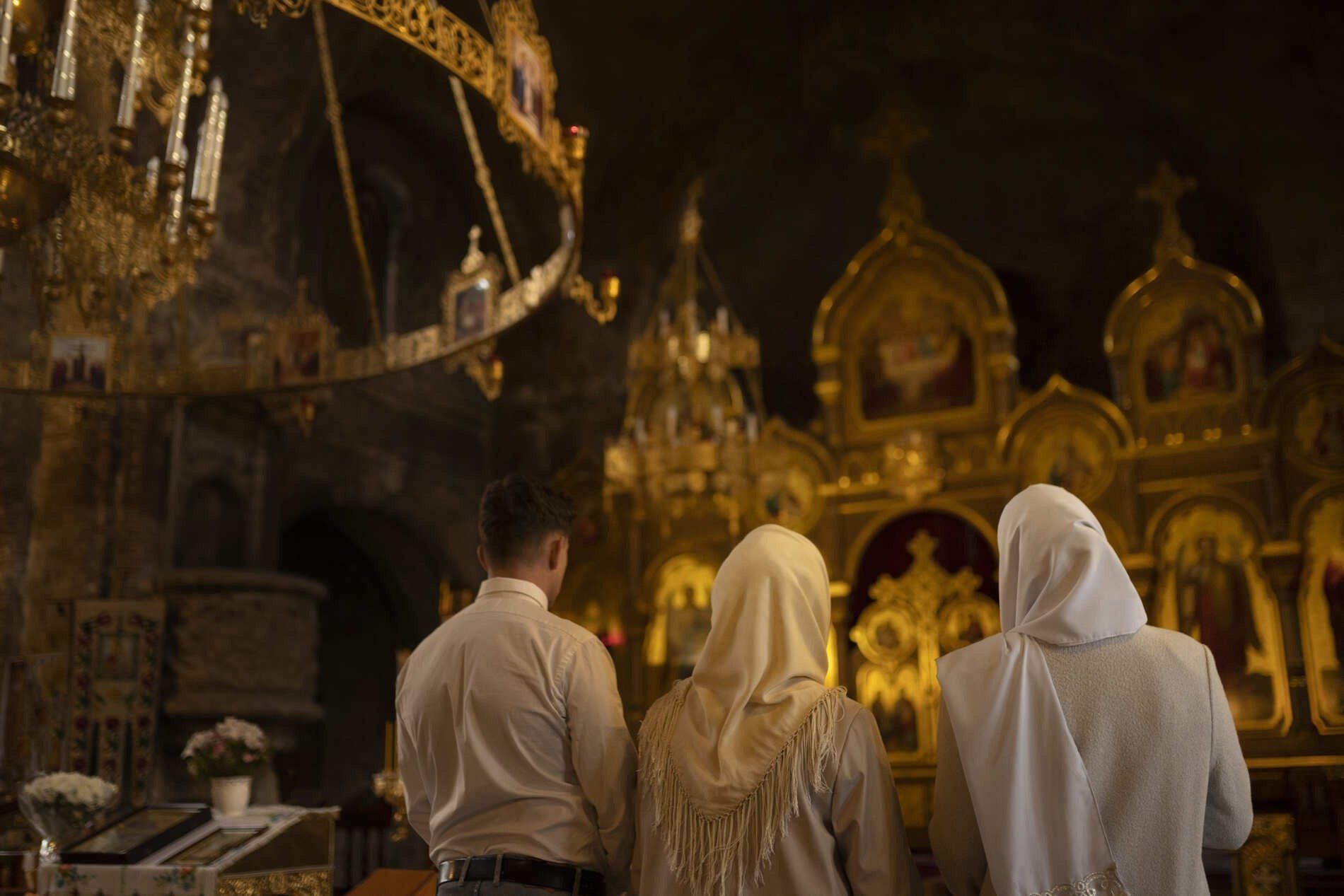 a man and two women are praying in a church