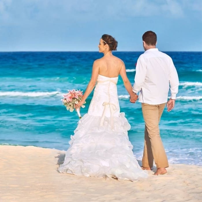 Casal de noivos caminhando ao longo da costa da praia do Hotel Park Royal Beach Cancun