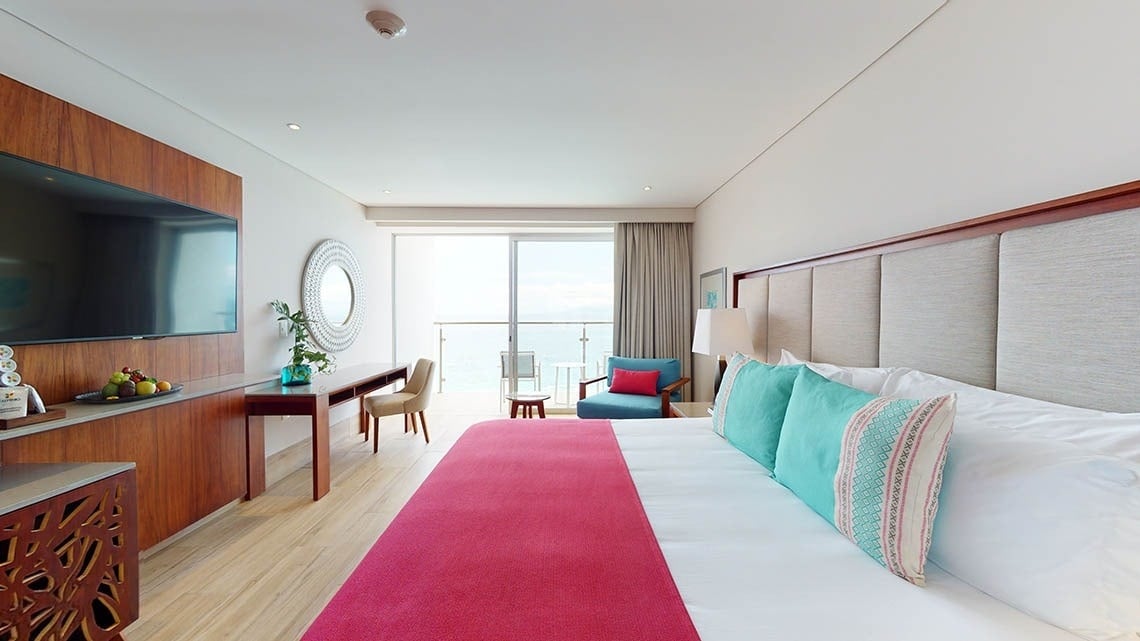 Grande quarto com cama, espelho e varanda com vista para o mar no Hotel Grand Park Royal Puerto Vallarta