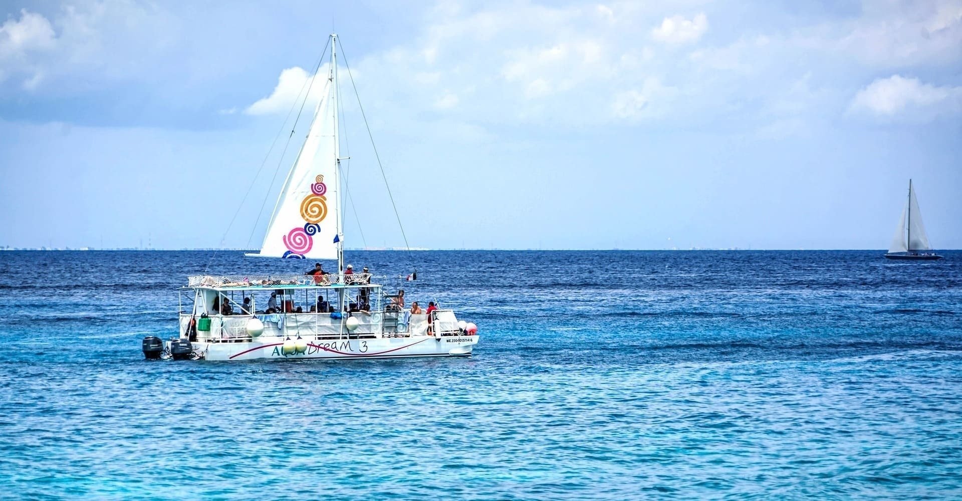 a sailboat with a colorful sail is floating in the ocean