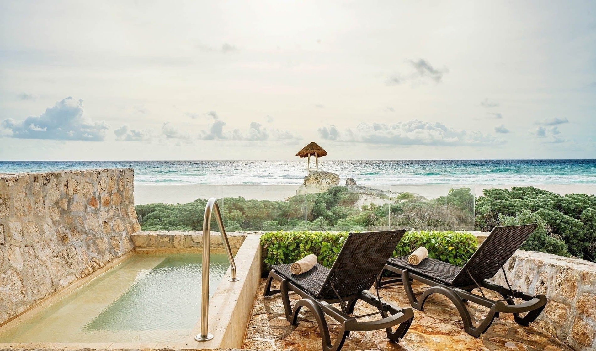 two lounge chairs sit next to a pool overlooking the ocean