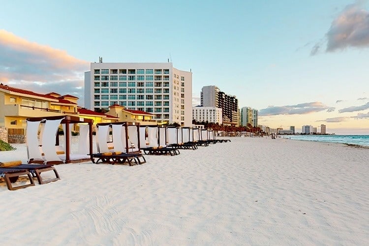 una fila de sillas de playa en una playa con un edificio en el fondo