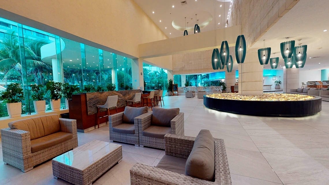 Lobby with armchairs and blue-toned lights at the Park Royal Beach Cancun Hotel