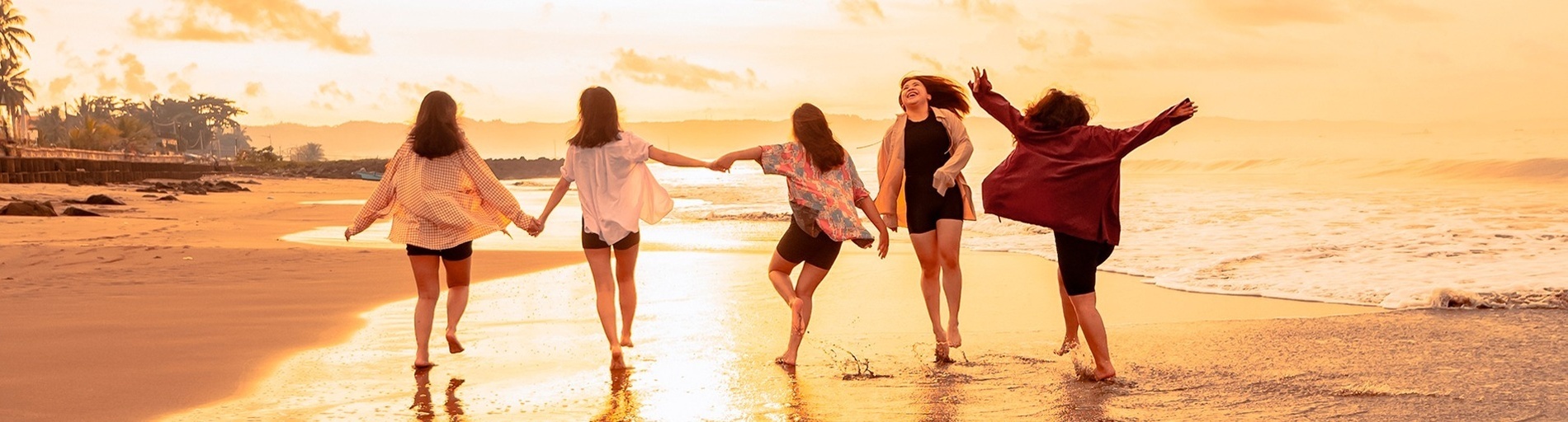a group of women are walking on a beach at sunset