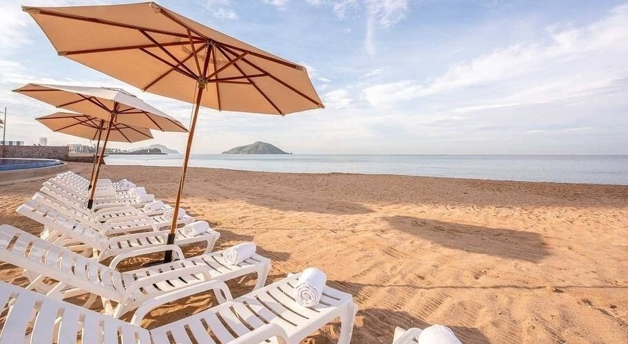 una playa con sillas y sombrillas y toallas en la arena