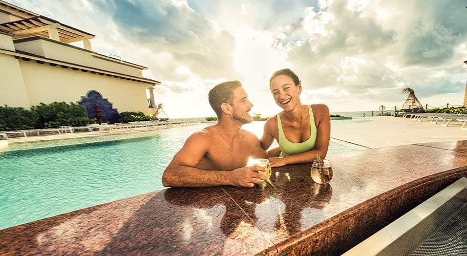 Pareja en piscina de dos niveles con vistas al mar de Park Royal Grand Cancún