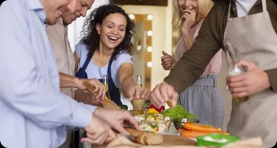 a group of people are cooking together in a kitchen.