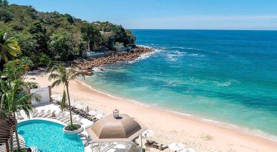 Resort na praia de Puerto Vallarta com piscina e mar turquesa.
