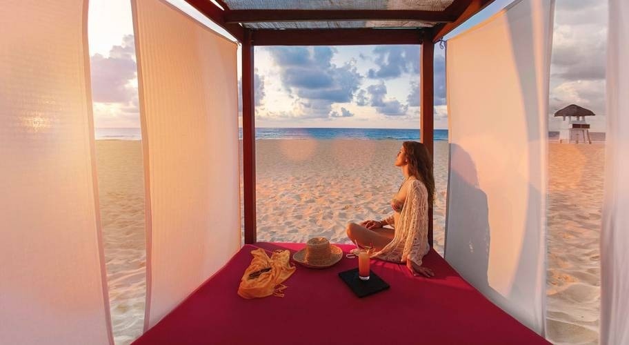 Mujer disfrutando del atardecer en una cama balinesa de Park Royal Grand Cancún