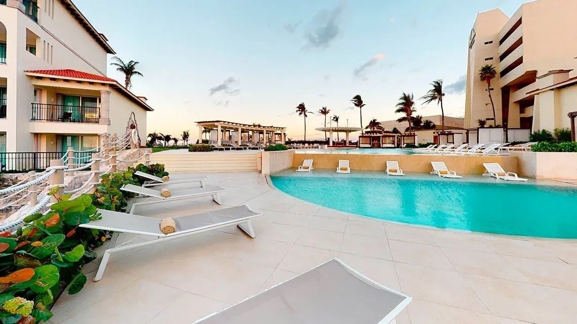 a large swimming pool surrounded by lounge chairs and palm trees