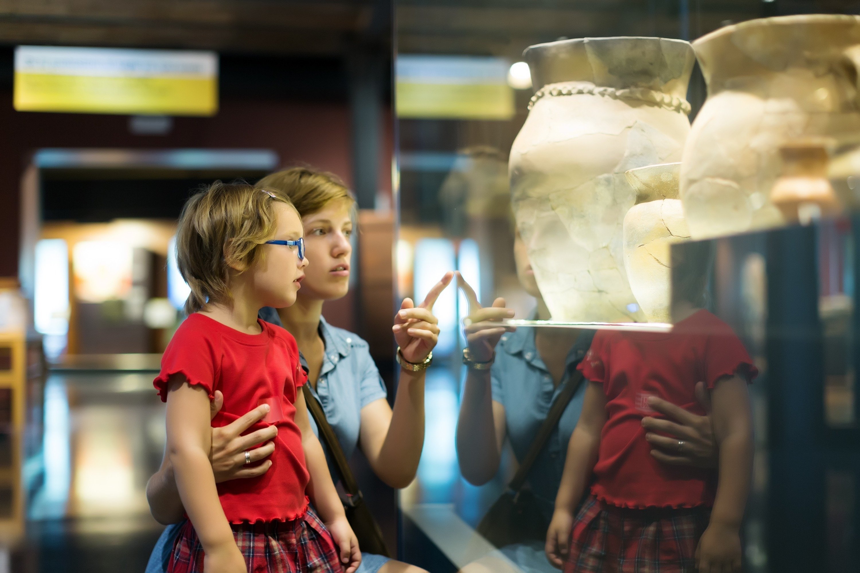 uma mulher e uma criança olham para um vaso em uma vitrine