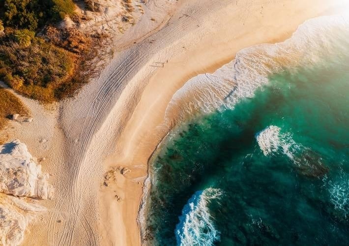 an aerial view of a beach with waves crashing on the shore .