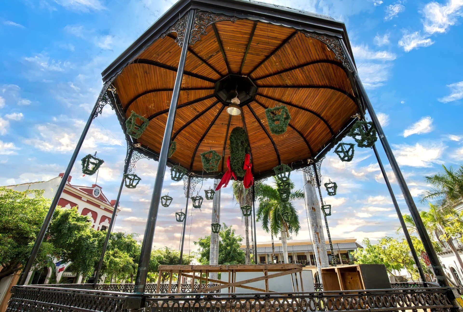 a gazebo with a wooden roof and lanterns hanging from it