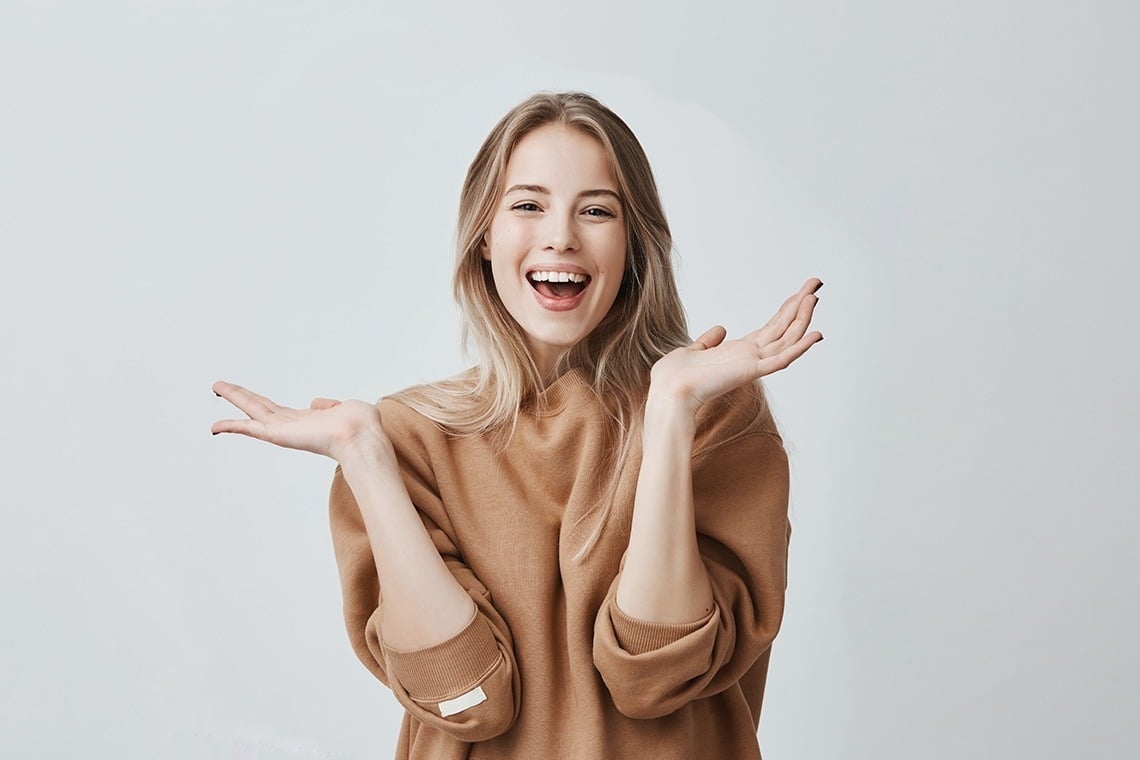 a woman in a brown sweater is laughing with her mouth open