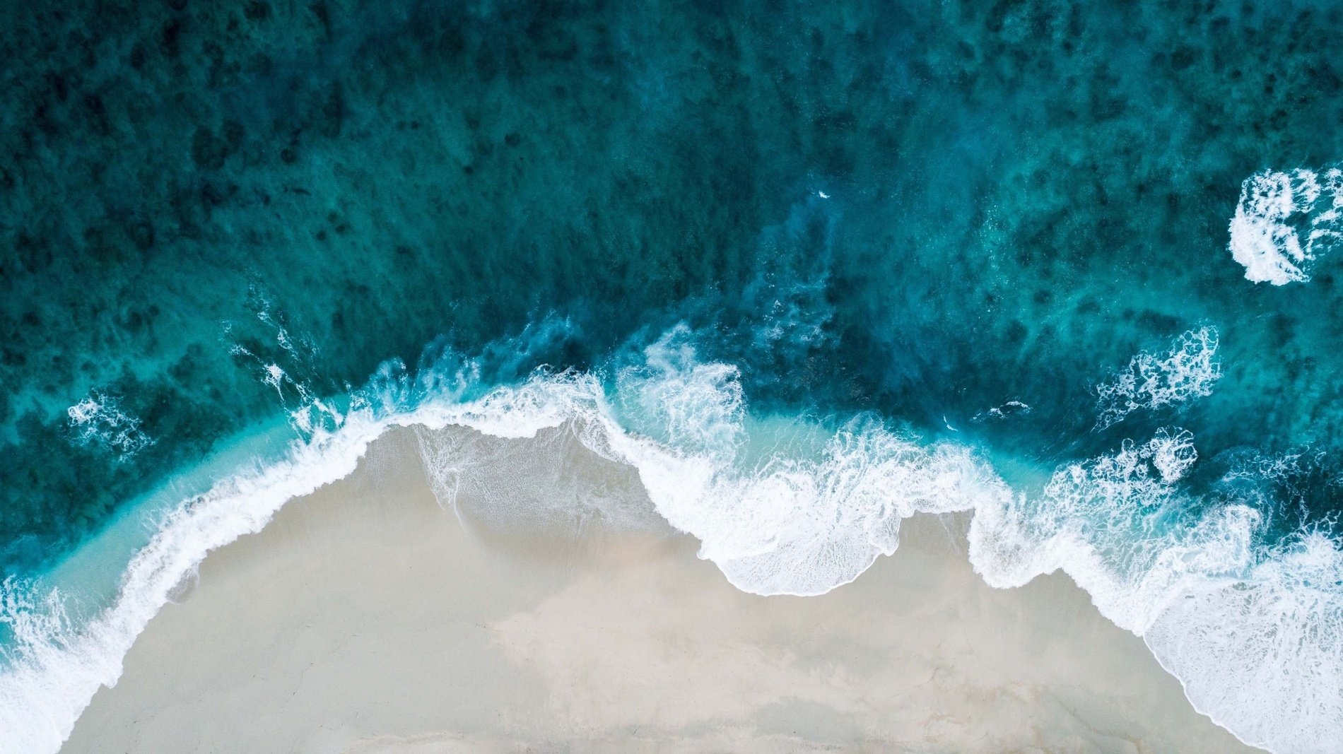 una vista aérea de las olas rompiendo en la playa