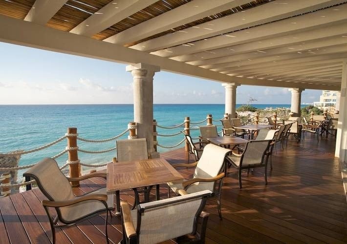 tables and chairs on a deck overlooking the ocean