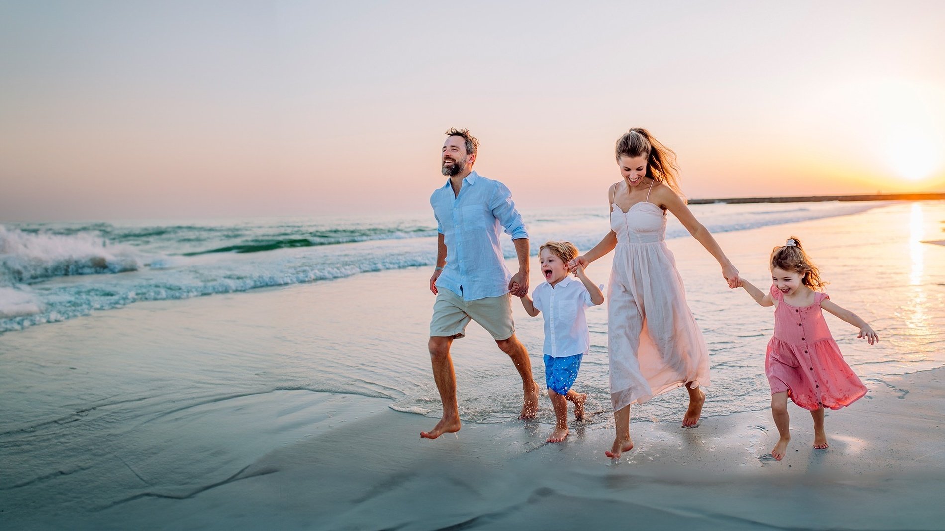 a family walking on the beach holding hands