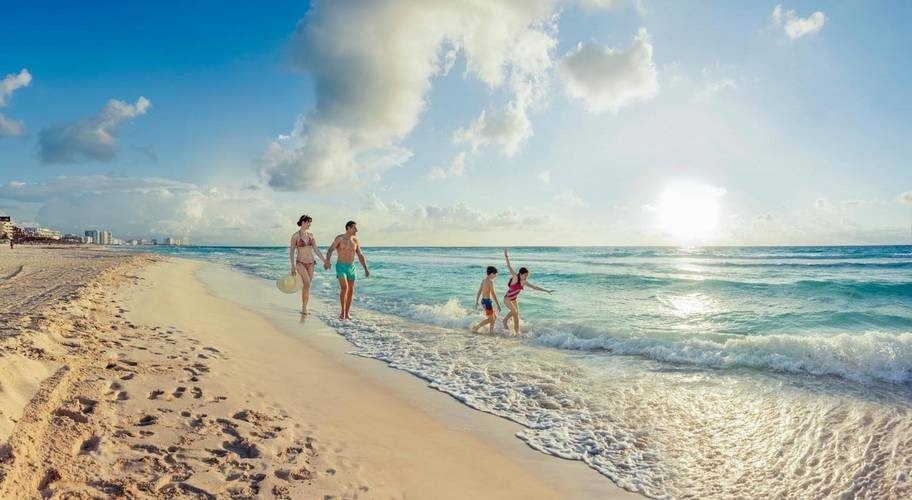 Parents and children enjoying on the shore of the beach of the Hotel Park Royal Beach Cancun