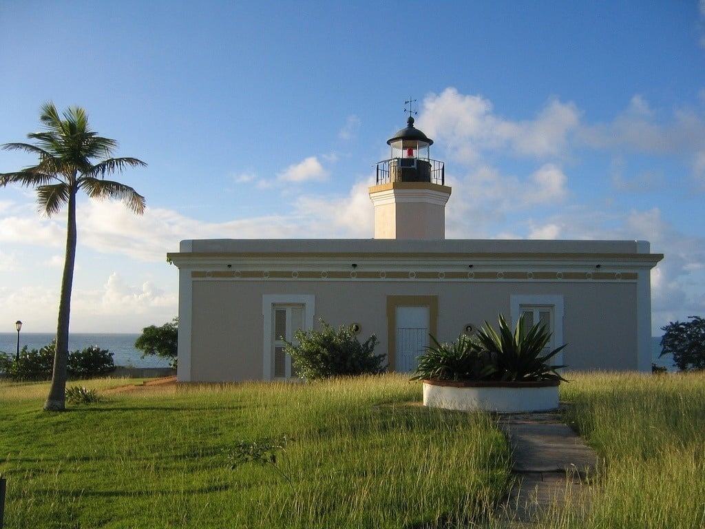 um farol com uma palmeira ao fundo e o oceano ao fundo