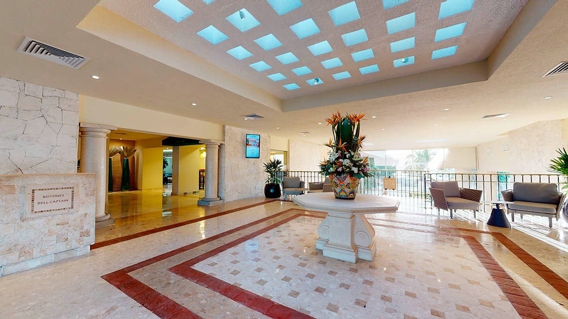 Lobby con mesa y jarrón de flores del Hotel Grand Park Royal Cancún