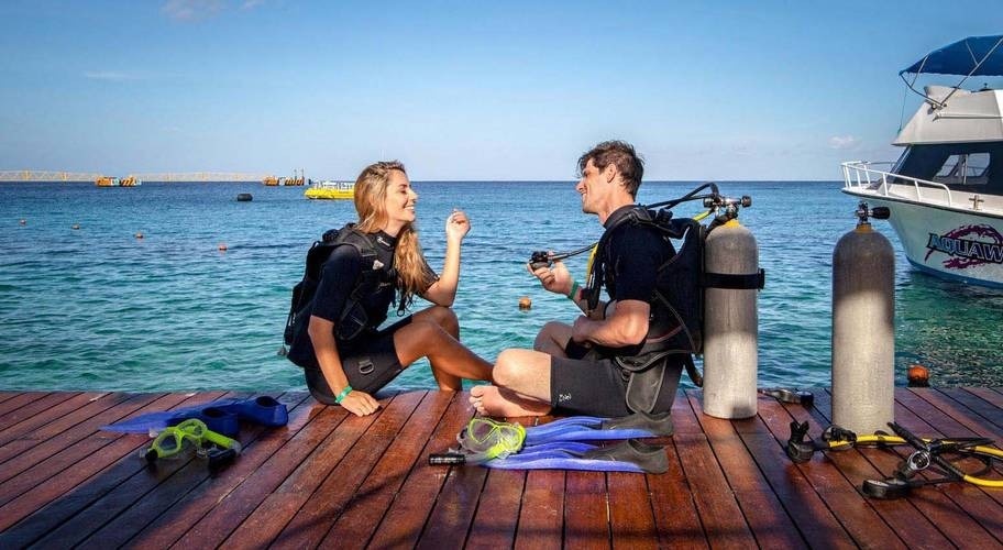 Casal no cais se preparando para mergulhar no Caribe mexicano no Grand Park Royal Cozumel Hotel