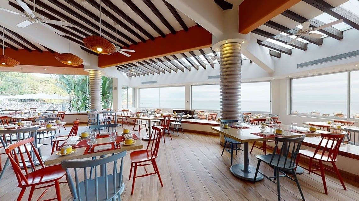 Área de restaurante con sillas y mesas, con vistas al mar del Hotel Grand Park Royal Puerto Vallarta