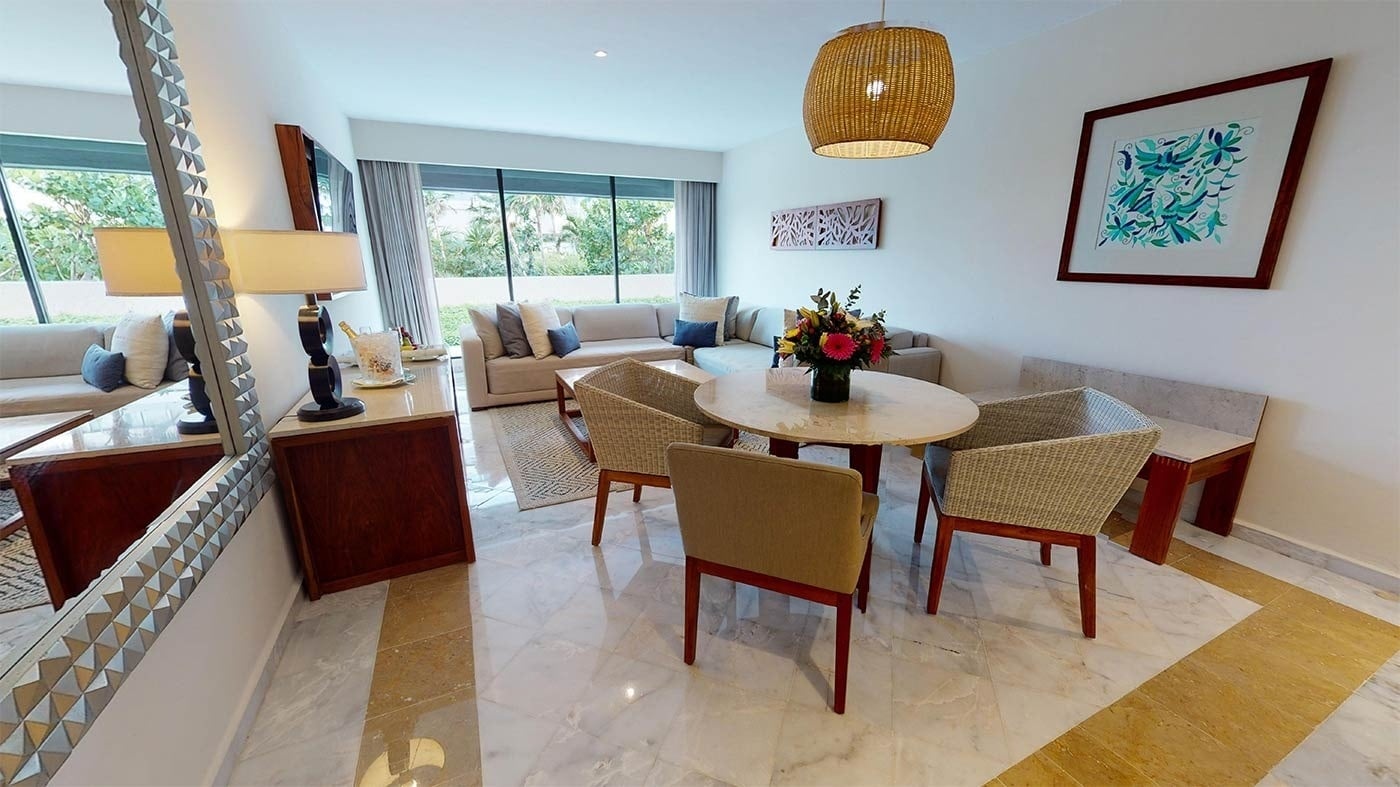 Elegante sala de estar y comedor con muebles de mimbre y arte local en Hotel Park Royal Beach Cancún | Caribe Mexicano | Web oficial.