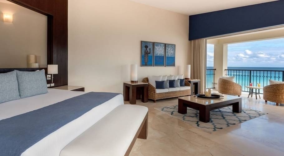Room with a king size bed and sofas, with views of the Caribbean Sea at the Grand Park Royal Cancun Hotel