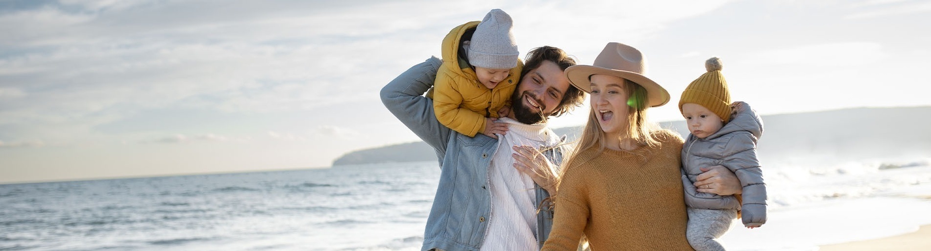 a family standing on a beach with two children on their shoulders