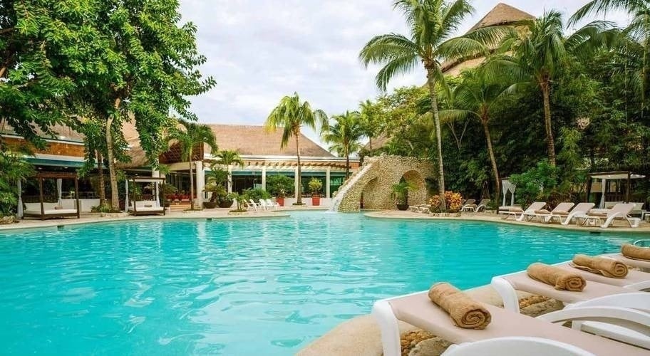 a large swimming pool surrounded by chairs and palm trees