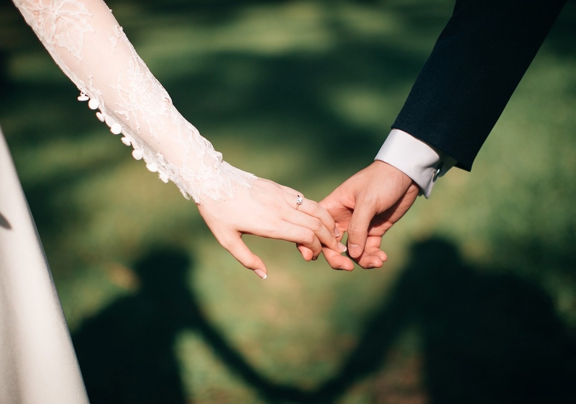 a bride and groom hold hands with their shadows behind them